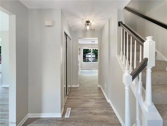 hallway featuring light wood-type flooring and a notable chandelier