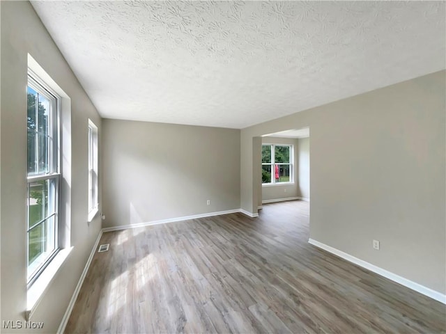 unfurnished room with a textured ceiling and hardwood / wood-style floors