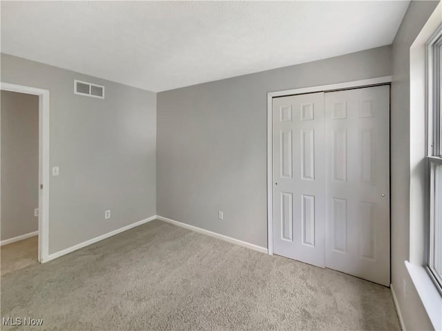 unfurnished bedroom with light carpet and a closet