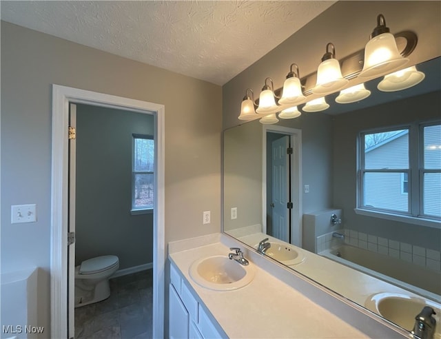 bathroom featuring a textured ceiling, toilet, vanity, and a bathing tub