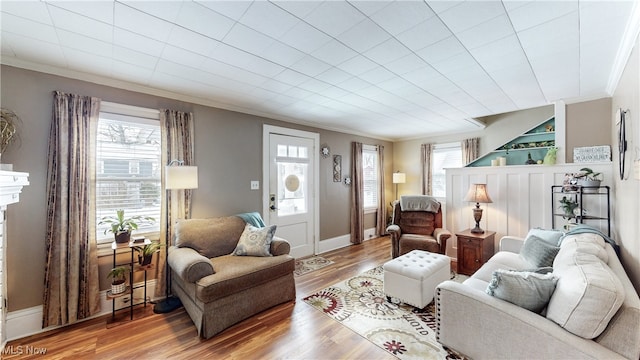 living room featuring built in shelves, wood-type flooring, and ornamental molding