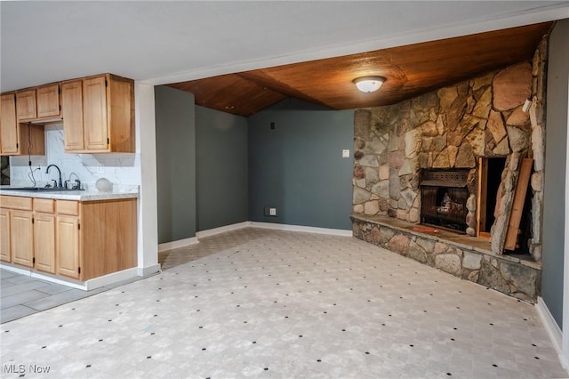 kitchen featuring light brown cabinetry, a fireplace, tasteful backsplash, and sink