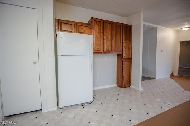 kitchen featuring white refrigerator and a textured ceiling