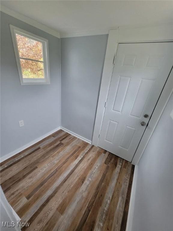 unfurnished bedroom featuring a closet, crown molding, and hardwood / wood-style floors