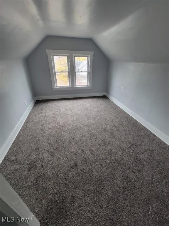 bonus room with vaulted ceiling and carpet flooring