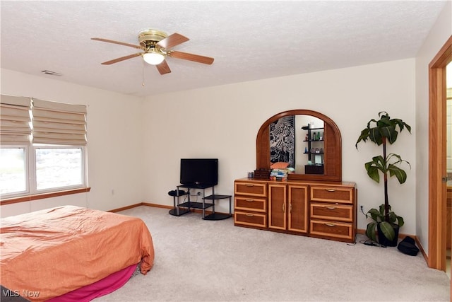 bedroom with ceiling fan, light colored carpet, and a textured ceiling