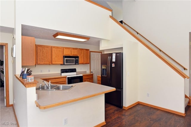 kitchen featuring black fridge, white electric stove, kitchen peninsula, and sink