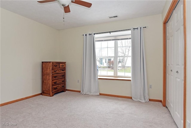 unfurnished bedroom featuring ceiling fan, multiple windows, a closet, and light carpet