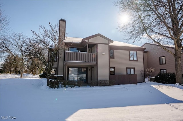 snow covered back of property featuring a balcony