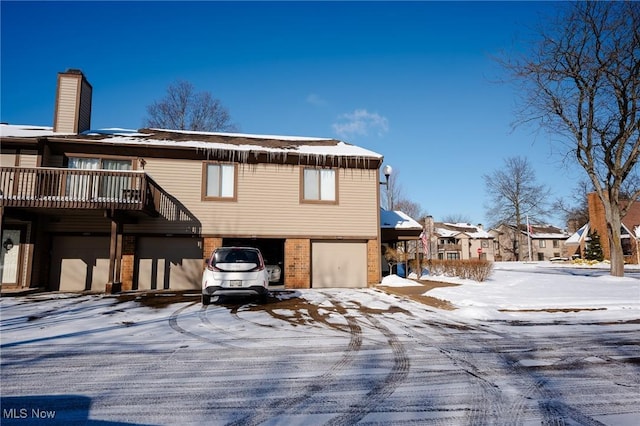 snow covered house featuring a garage and a balcony