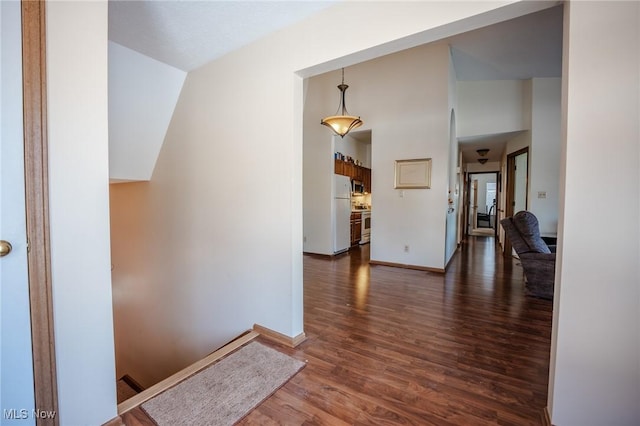 hallway with lofted ceiling and dark wood-type flooring