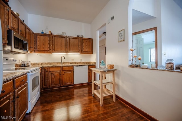 kitchen with dark hardwood / wood-style floors, sink, white appliances, and light stone counters