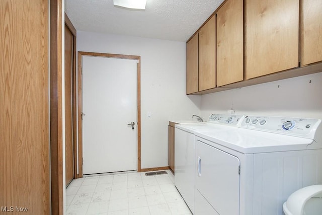 washroom featuring cabinets, a textured ceiling, and independent washer and dryer