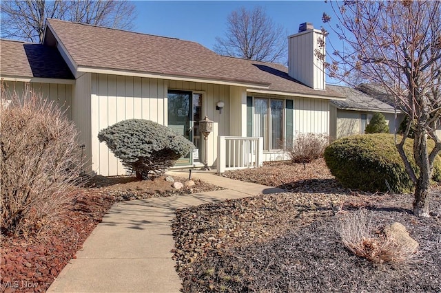 rear view of property with roof with shingles and a chimney