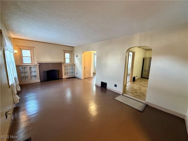 unfurnished living room with a brick fireplace and a textured ceiling