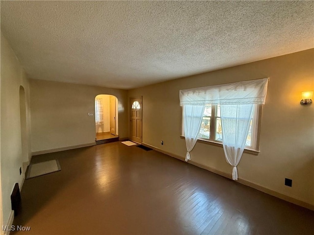 unfurnished room featuring a textured ceiling and dark hardwood / wood-style floors