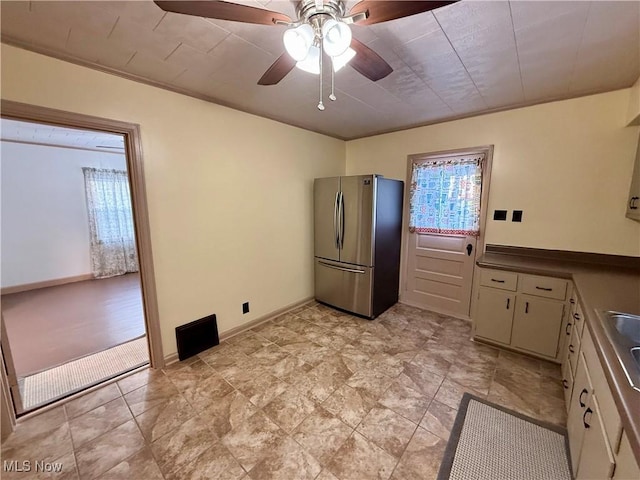 kitchen featuring ceiling fan, sink, crown molding, stainless steel fridge, and cream cabinets