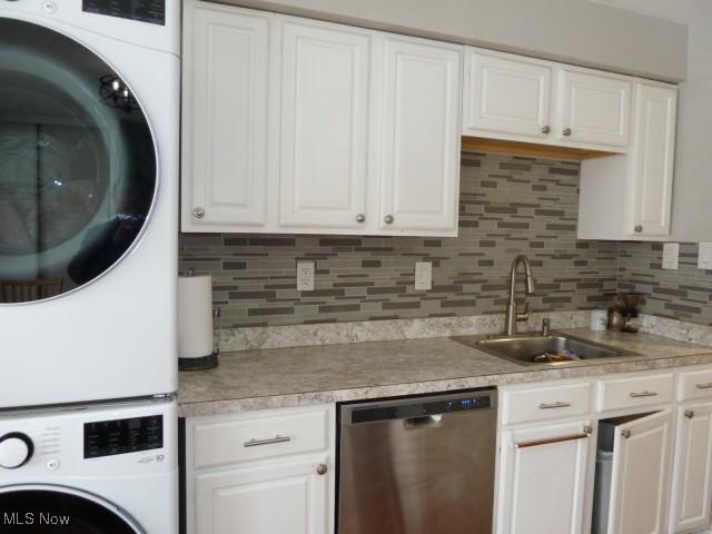 kitchen featuring stacked washer and dryer, white cabinetry, and stainless steel dishwasher