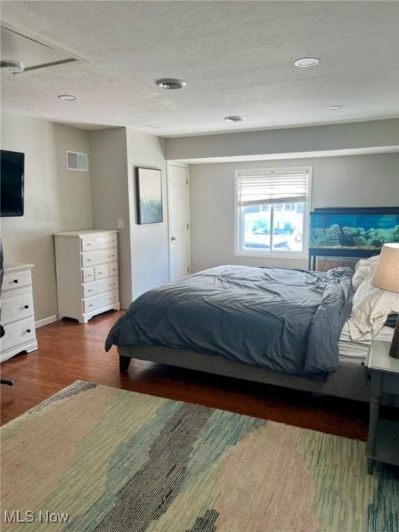 bedroom with dark hardwood / wood-style flooring and a textured ceiling