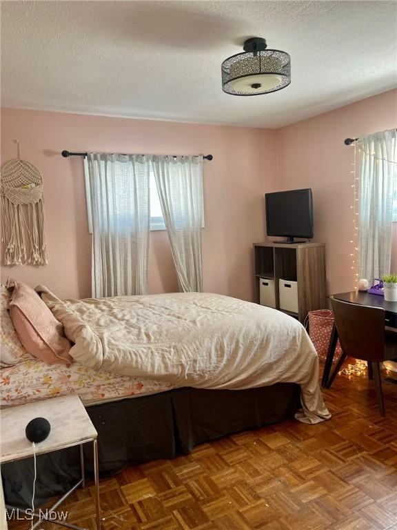 bedroom with a textured ceiling and parquet floors