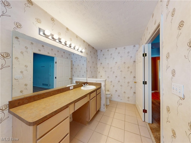 bathroom featuring toilet, vanity, tile patterned flooring, and a textured ceiling