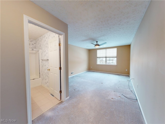 unfurnished room featuring a textured ceiling, ceiling fan, and light colored carpet