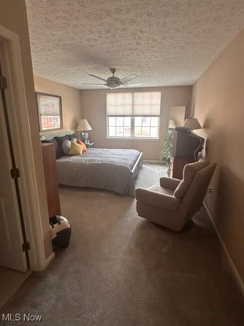 bedroom featuring ceiling fan, a textured ceiling, and carpet floors