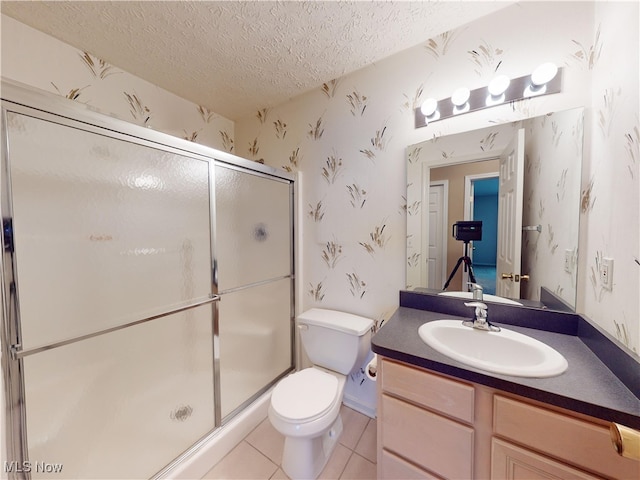 bathroom featuring a textured ceiling, tile patterned floors, vanity, toilet, and a shower with shower door