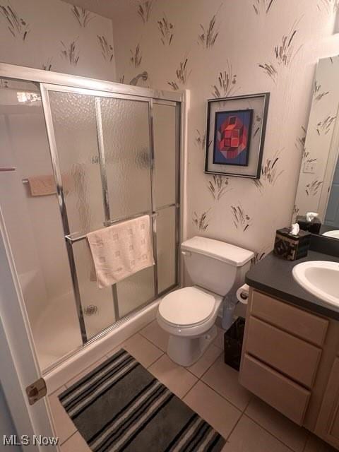 bathroom with a shower with shower door, tile patterned floors, vanity, and toilet