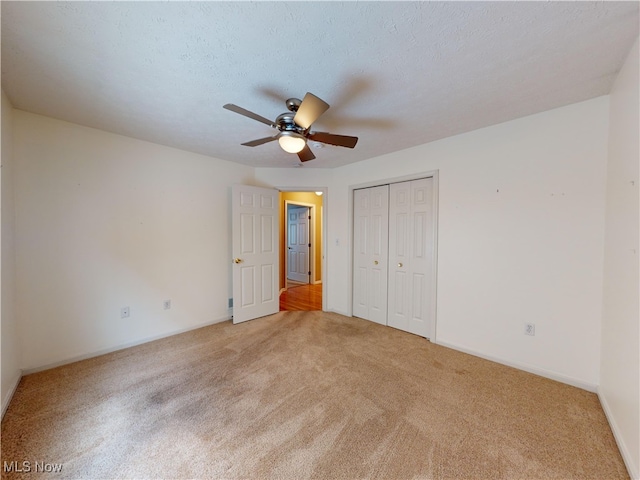 unfurnished bedroom with a textured ceiling, ceiling fan, a closet, and light colored carpet