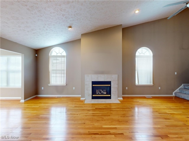 unfurnished living room featuring a textured ceiling, lofted ceiling, and light hardwood / wood-style flooring