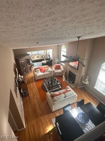 living room featuring a textured ceiling, ceiling fan, and hardwood / wood-style floors