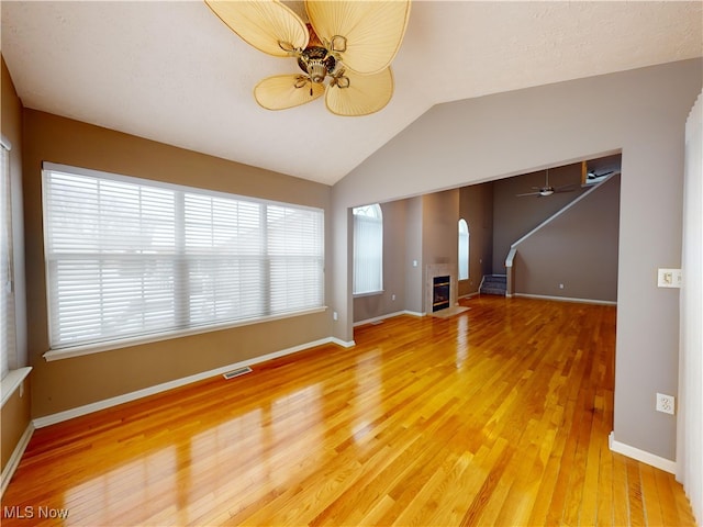 unfurnished living room featuring ceiling fan, lofted ceiling, a fireplace, and hardwood / wood-style floors