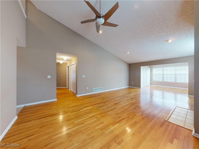 unfurnished living room with ceiling fan, a textured ceiling, high vaulted ceiling, and light wood-type flooring