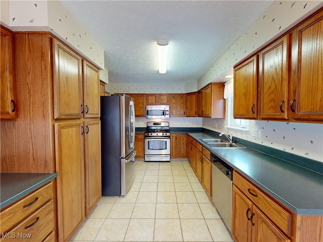 kitchen with light tile patterned floors, appliances with stainless steel finishes, sink, and a textured ceiling