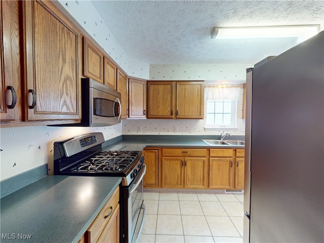 kitchen featuring a textured ceiling, light tile patterned floors, appliances with stainless steel finishes, and sink