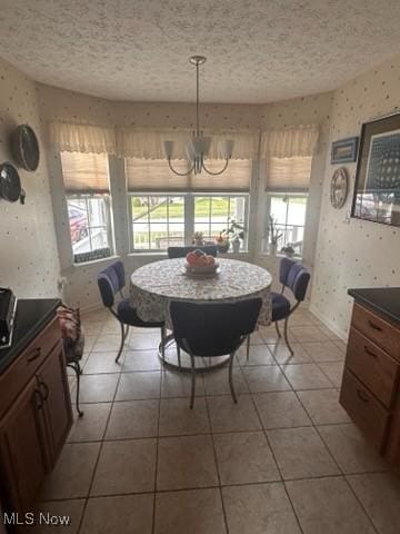 tiled dining space with a textured ceiling, a wealth of natural light, and a chandelier