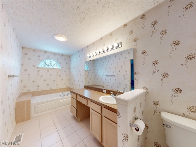 bathroom featuring toilet, vanity, tile patterned floors, a textured ceiling, and a bathtub