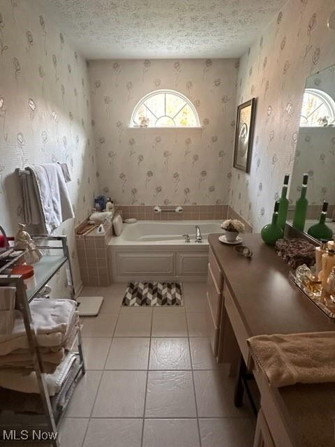 bathroom with a textured ceiling, a wealth of natural light, tile patterned floors, and a washtub