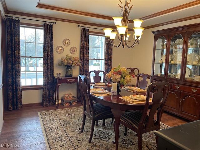 dining room featuring dark hardwood / wood-style flooring, an inviting chandelier, ornamental molding, and a tray ceiling