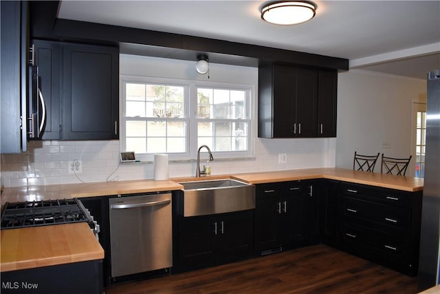 kitchen featuring appliances with stainless steel finishes, backsplash, wooden counters, and sink