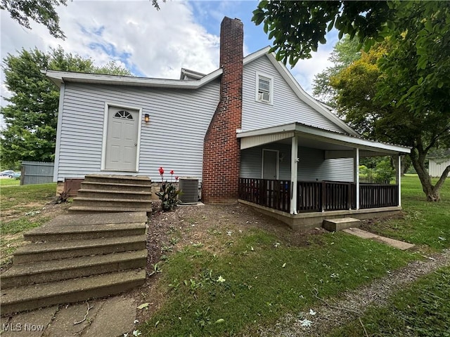 view of front of home with a front yard, central AC unit, and a porch