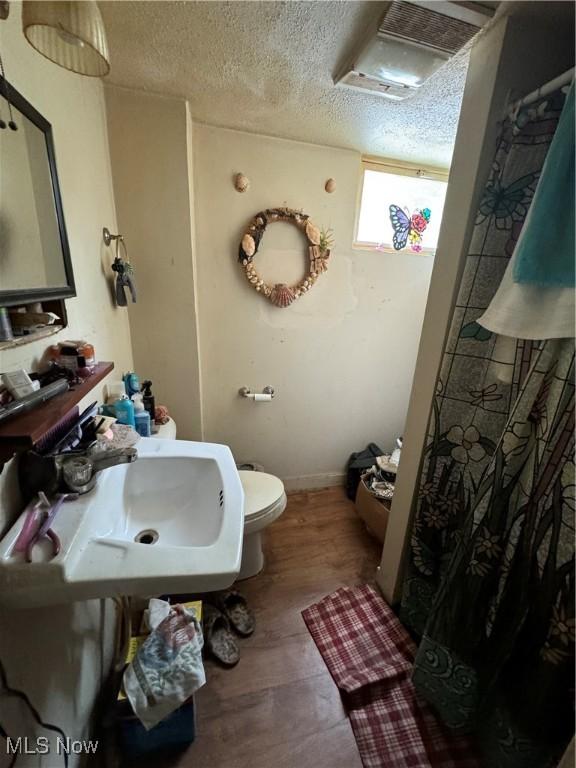 bathroom with sink, a textured ceiling, and toilet