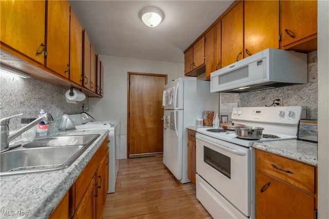 kitchen with washing machine and clothes dryer, decorative backsplash, white appliances, light wood-type flooring, and sink