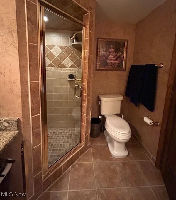 bathroom with a shower with shower door, vanity, tile patterned flooring, and toilet