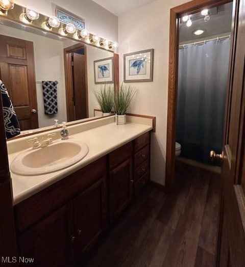 bathroom featuring toilet, a shower with curtain, hardwood / wood-style floors, and vanity