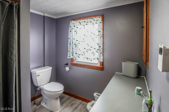 bathroom featuring toilet, a wealth of natural light, crown molding, and hardwood / wood-style floors