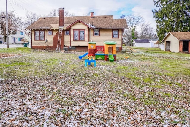 rear view of house featuring a lawn, central AC unit, and a playground