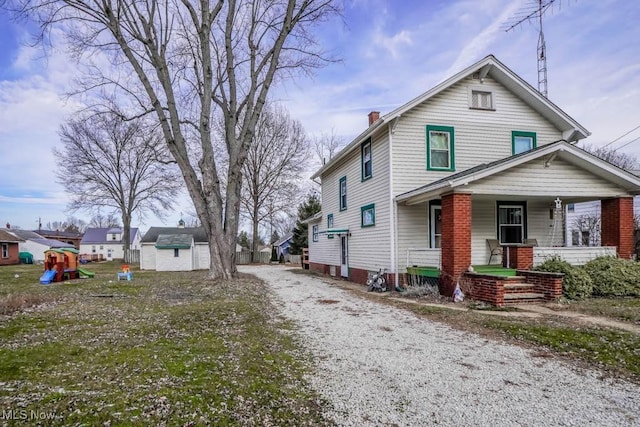 view of front of property with a playground, a storage shed, and a porch