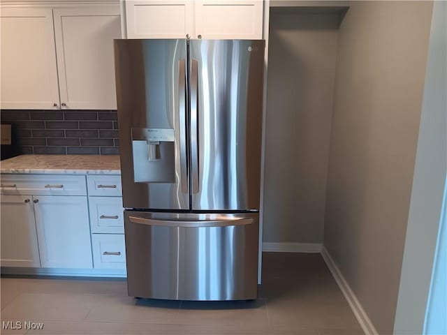 kitchen with light stone countertops, white cabinets, backsplash, stainless steel fridge with ice dispenser, and light tile patterned flooring